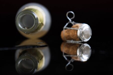 Last drop of champagne. Opened wine bottle lays on a table. From her champagne flowsの写真素材