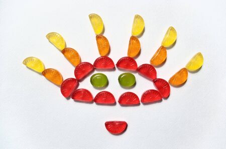 Funny sun combined from sugar candies on a white paperの写真素材