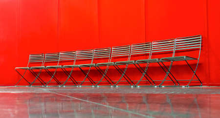 Set of metal chairs close to red wallの写真素材