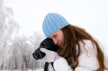 Beautiful girl making photos outdoor in winterの写真素材