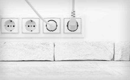 Electric plugs in a socket in the white interiorの写真素材