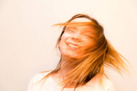Closeup young beautiful girl with red hair flying against white backgroundの写真素材