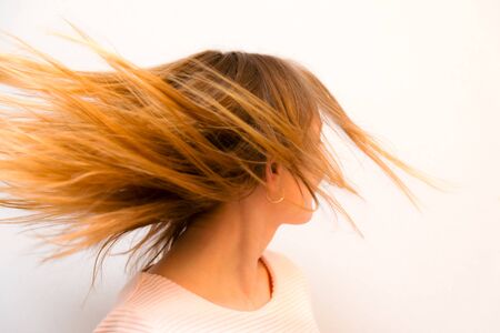 Closeup young beautiful girl with red hair flying against white backgroundの写真素材