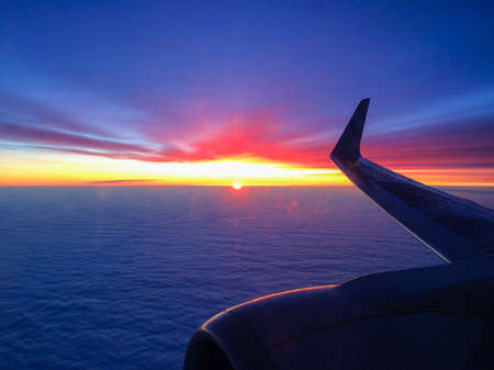 Wing of a plane in clouds at sunset.の写真素材
