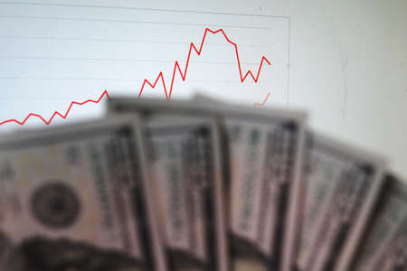 a bunch of dollar bills in front a market chart