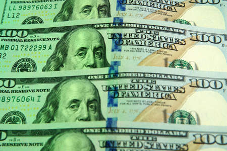 Close view of a bunch of 100 dollar bills. Under a green and white lights