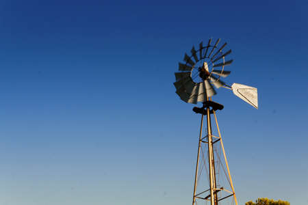 Isolated old metal windmill located in Brandsen, Buenos Aires, Argentina. taken from the ground level, looking to the top of the mill. Clear blue sky as a background. Shooted in a summer afternoon.の写真素材