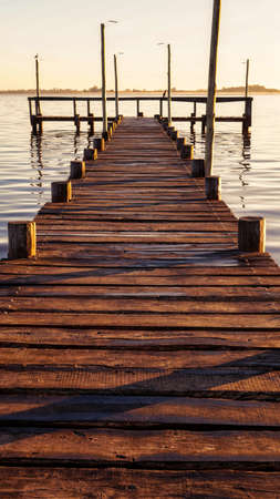 Sunset at Lobos lake, Buenos Aires. Taken from the shore looking to an old large wooden pier and the lakeの写真素材
