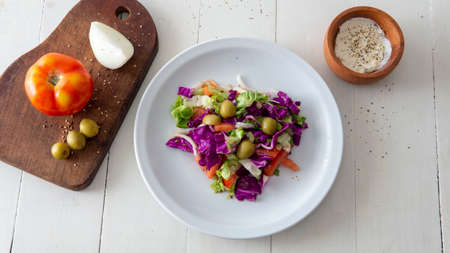 Flat lay view of a fresh Mediterranean style salad, placed on top of a white table