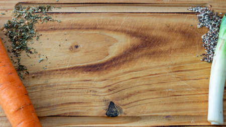 Background with copy space of a mix of spices, carrot, seeds mix and leek over a rustic wooden cutting boardの写真素材