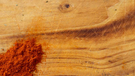 Red paprika powder over a rustic wooden cutting board background with copy spaceの写真素材