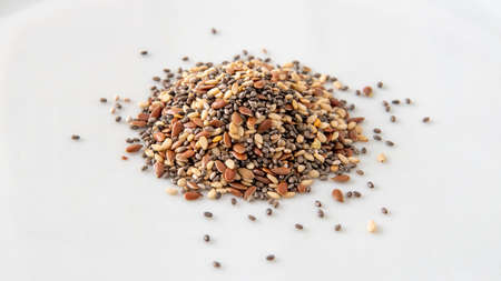 Close view of a small pile of chia, flax and sesame seeds over a white backgroundの写真素材