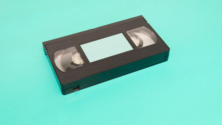 Close view of an old VHS tape with a blank label over a cyan surfaceの写真素材