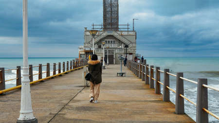 Young woman walking in a concrete old pier with Mar del Plata fishing club behindのeditorial素材