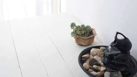 Close view of a zen water fountain with a small succulent plant behind. Placed on top of a white...