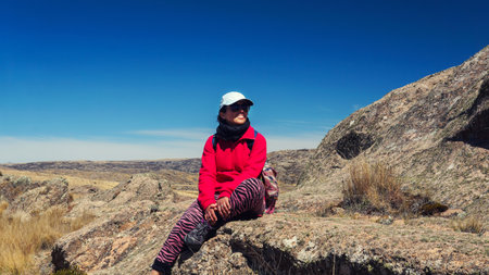Young woman hiking in "quebrada del condorito" national park. surrounded by a few hills, rocks and golden color vegetationの写真素材
