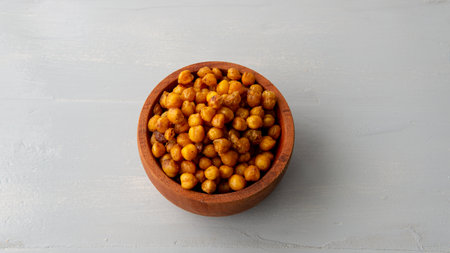 flat lay view of a wooden bowl filled with salty crispy chickpeas. over a white wooden tableの写真素材