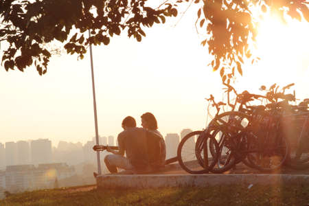 Couple in love sitting on a bench in the park at sunsetの写真素材