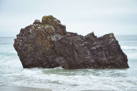 Surf breaking around a rockの写真素材