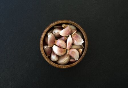 fresh garlic in a wooden bowl on black backgroundの写真素材
