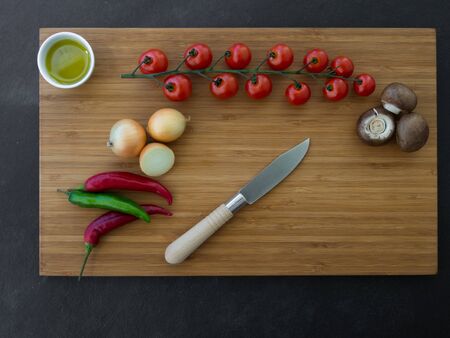 Fresh vegetables, olive oil and knife on wooden backgroundの写真素材