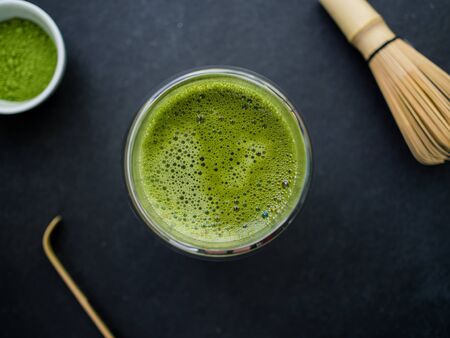 matcha green tea in a cup and bamboo wisk on slate backgroundの写真素材