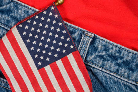 A small American flag against a pair of blue jeans and a t-shirtの写真素材