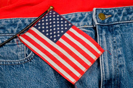 A small American flag against a pair of blue jeans and a t-shirtの写真素材