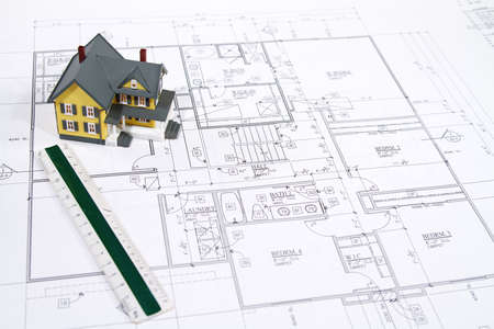 Residential home blueprints with a hand-made house model.