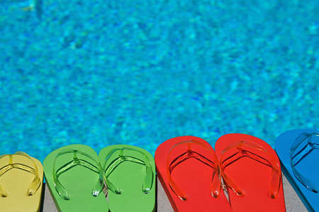 Colored flipflops of a family of four by the swimming poolの写真素材