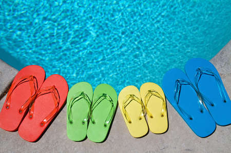 Colored flipflops of a family of four by the swimming poolの写真素材