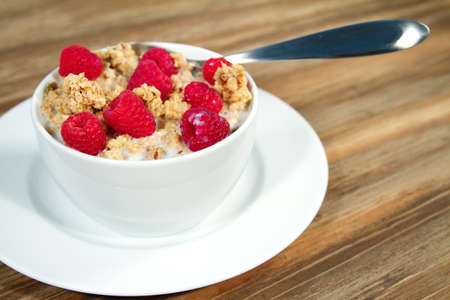 Fresh morning bowl of granola and raspberries with milk
