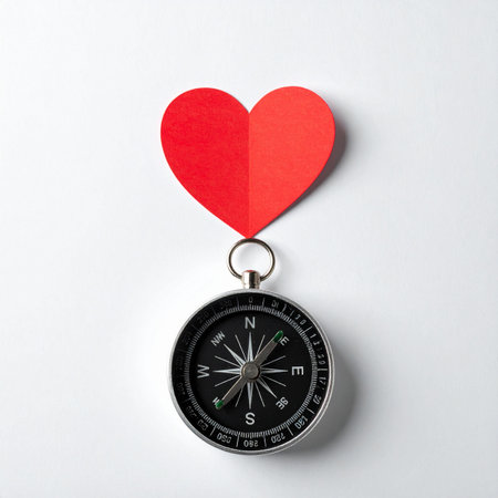 A conceptual image symbolizing the journey of love and self-discovery. A classic compass lies on a clean white background, guided by a vibrant red heart, illustrating the proverb to follow your heart in lifes most important decisions and relationships.の素材