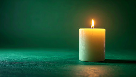 A single candle burns brightly, its warm flame a beacon of hope and tranquility in the quiet darkness. The soft glow reflects on the surface, creating an atmosphere of peace, contemplation, and remembrance.の素材