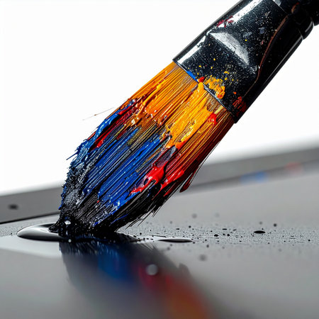 A close-up macro shot captures the moment of creation. A paintbrush, heavily loaded with a vibrant mix of primary colors, touches a dark surface, ready to begin the first stroke of a new masterpiece.の素材