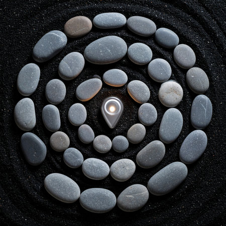 A spiral of smooth stones on dark sand leads the eye inward to a single, glowing location pin.の素材