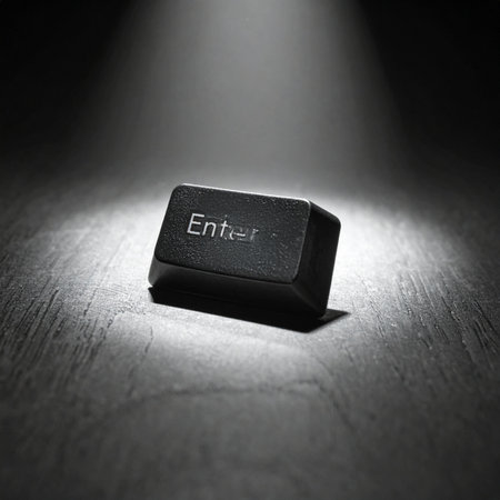 In a dramatic black and white scene, a single 'Enter' key is illuminated by a stark spotlight.の素材