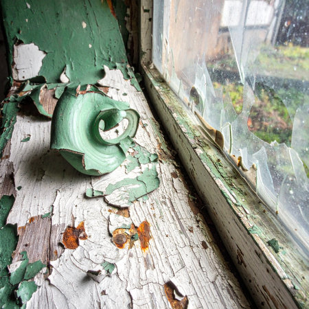A broken green teacup, a relic of a forgotten time, rests on a windowsill where layers of paint peel away like memories.の素材