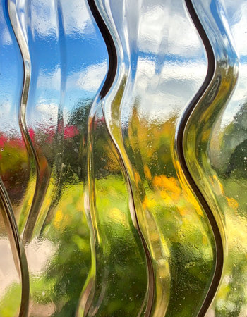 A vibrant summer garden is transformed into an impressionistic painting when viewed through the vertical waves of textured glass.の素材