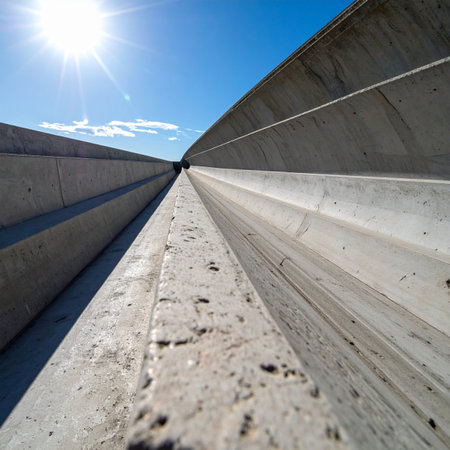 A low-angle perspective captures the powerful, converging lines of a modern concrete channel, creating a dramatic vanishing point under a brilliant blue sky.の素材
