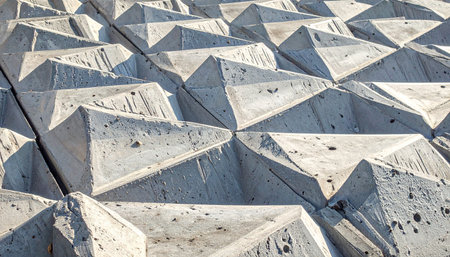 A close-up view of a brutalist architectural detail, where repeating concrete pyramids create a dynamic play of light and shadow.の素材