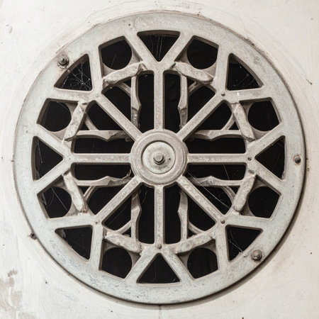 A close-up of an ornate, circular white metal vent grille, showcasing its intricate geometric pattern.の素材