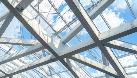 A view from below looking up through a complex geometric grid of steel beams and glass panels.の素材