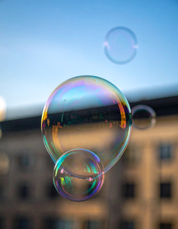 Delicate, iridescent soap bubbles drift peacefully through the air during a warm sunset.の素材