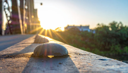 The last rays of the setting sun cast a warm, golden glow over the weathered steel of an old industrial bridge.の素材