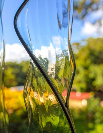 A glimpse of a vibrant summer garden seen through the surreal warp of rippled glass.の素材
