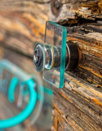 A close-up captures the timeless charm of an antique glass doorknob set against the deeply textured grain of a weathered wooden door.の素材