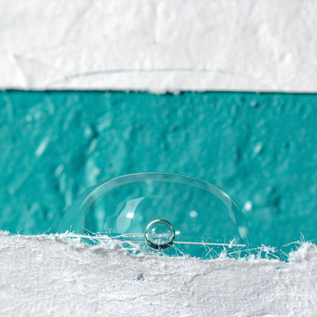A single, perfect bubble rests delicately on a textured white surface, poised against a vibrant turquoise horizon.の素材