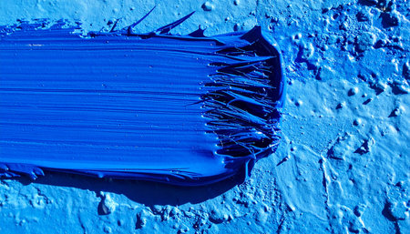 A single, bold stroke of vibrant blue oil paint is dragged across a textured canvas, capturing a moment of pure artistic expression.の素材
