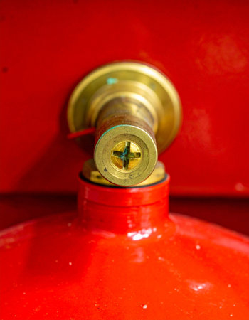 A detailed macro shot captures the brass valve of a bright red industrial gas canister.の素材